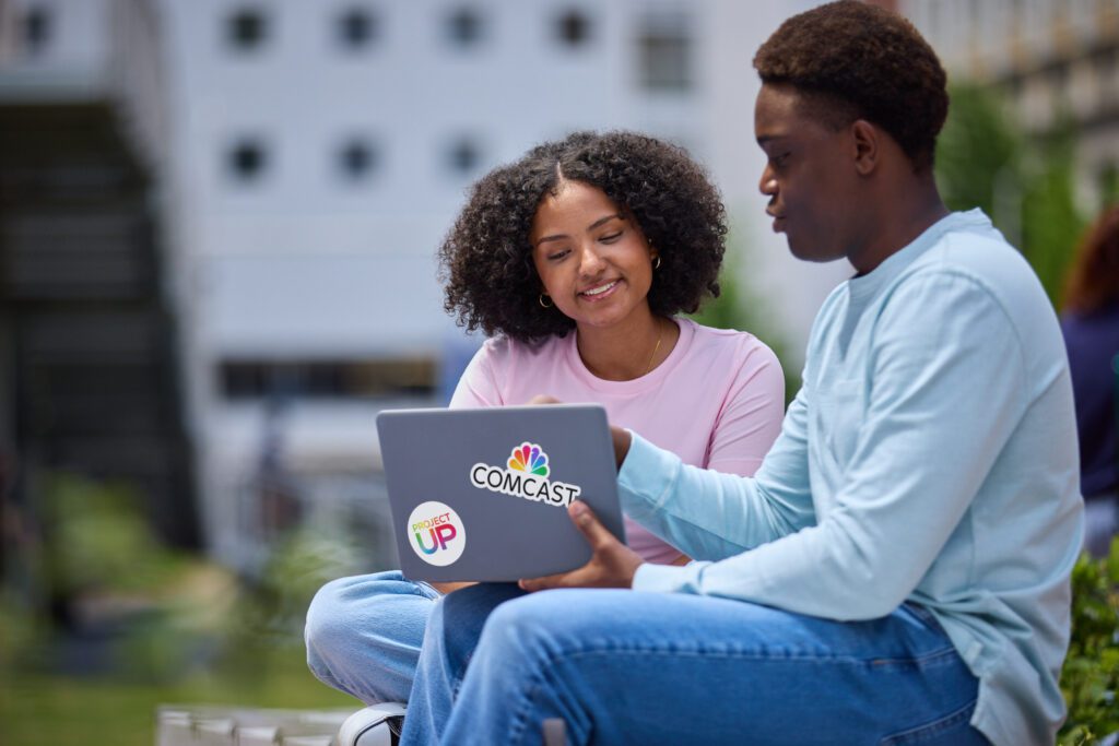 Two teens looking at a laptop in a recent network expansion area.