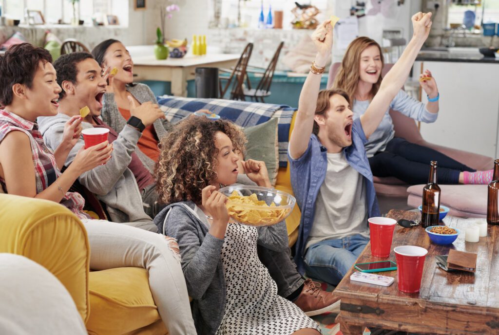 A group of people are watching basketball on a couch. March Madness fans are not only watching multiple games with Xfinity Multiview but keeping up with their March Madness brackets and scores only with Xfinity.