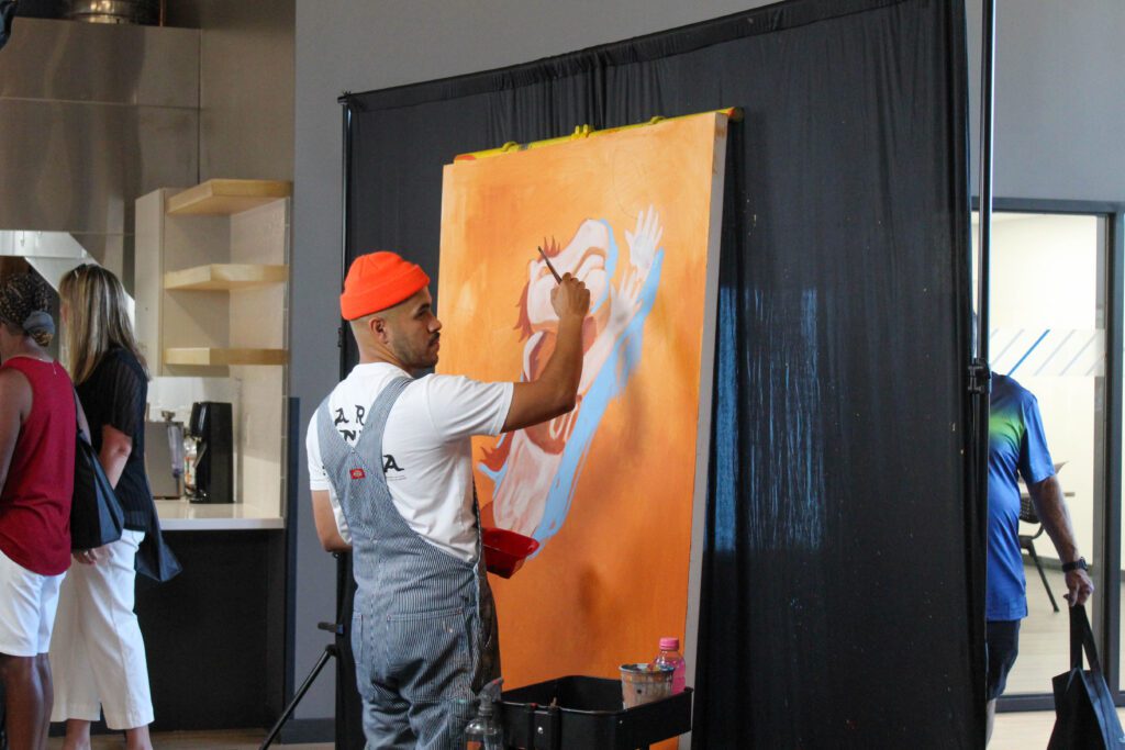 An artist painting Miles, the Denver Broncos mascot, at the Boys & Girls Clubs of Weld County's Teen Center grand opening event.