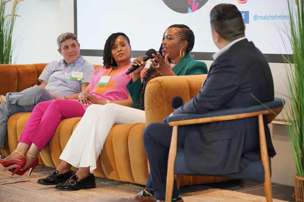 Panelists discuss owning a small business while sitting on a burnt orange sofa