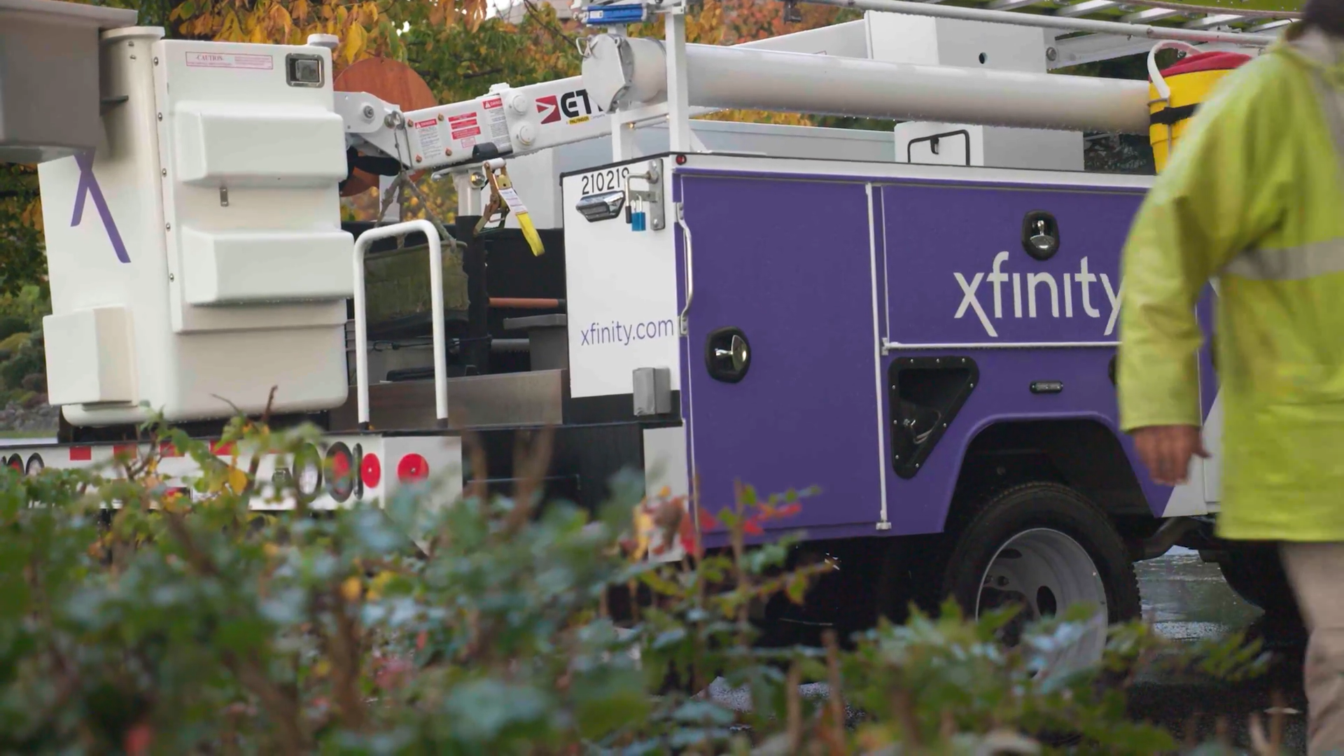 An Xfinity truck and a technician in a yellow jacket.