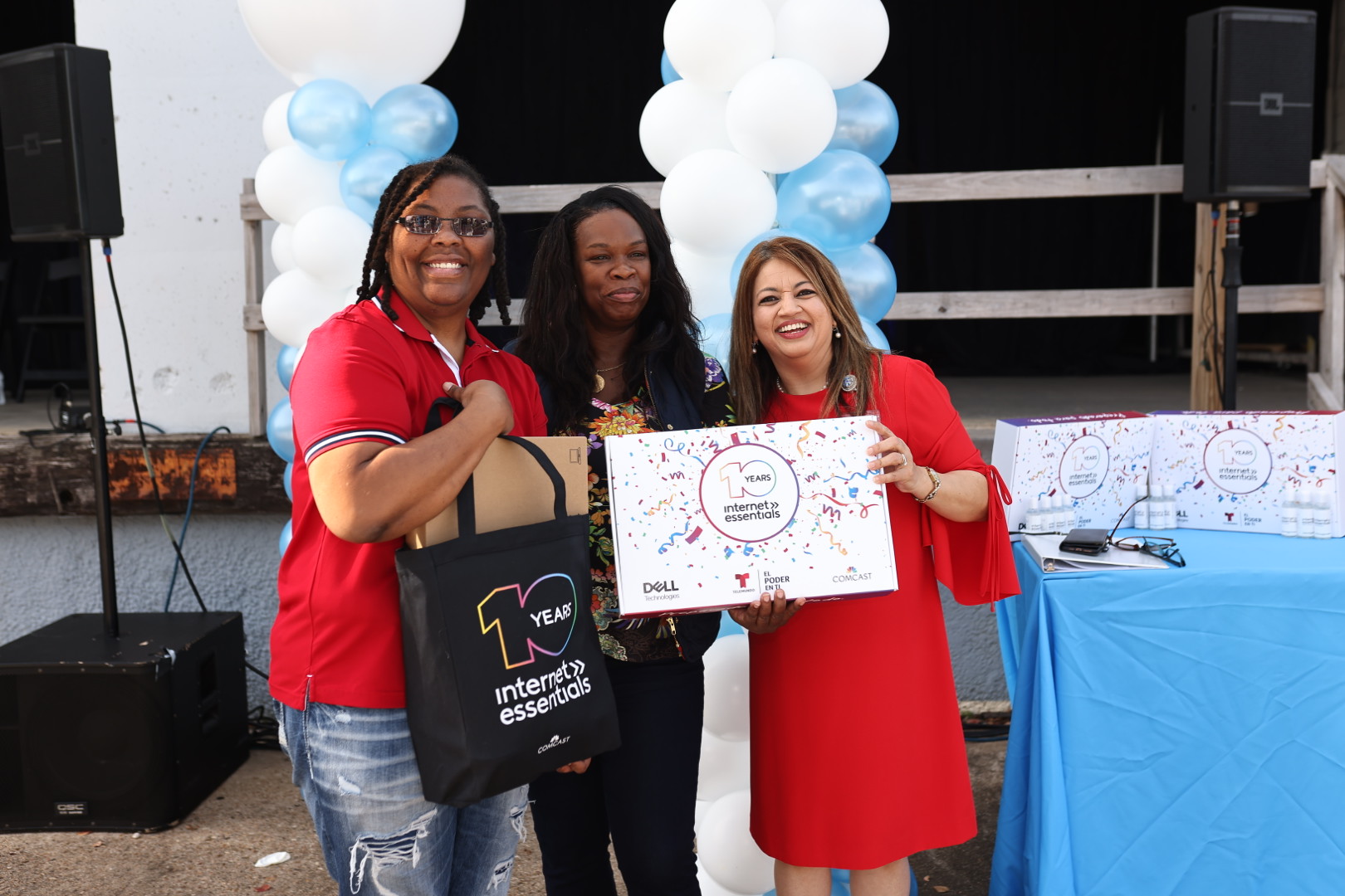 SERJobs volunteers hold up a free Internet Essentials laptop at a Project UP event.