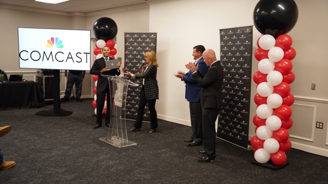 Comcast’s Bryce Kennard and Toni Beck show off one of the 150 laptops donated to Waller ISD families. Superintendent Kevin Moran and Waller County Judge Trey Duhon welcome the surprise announcement