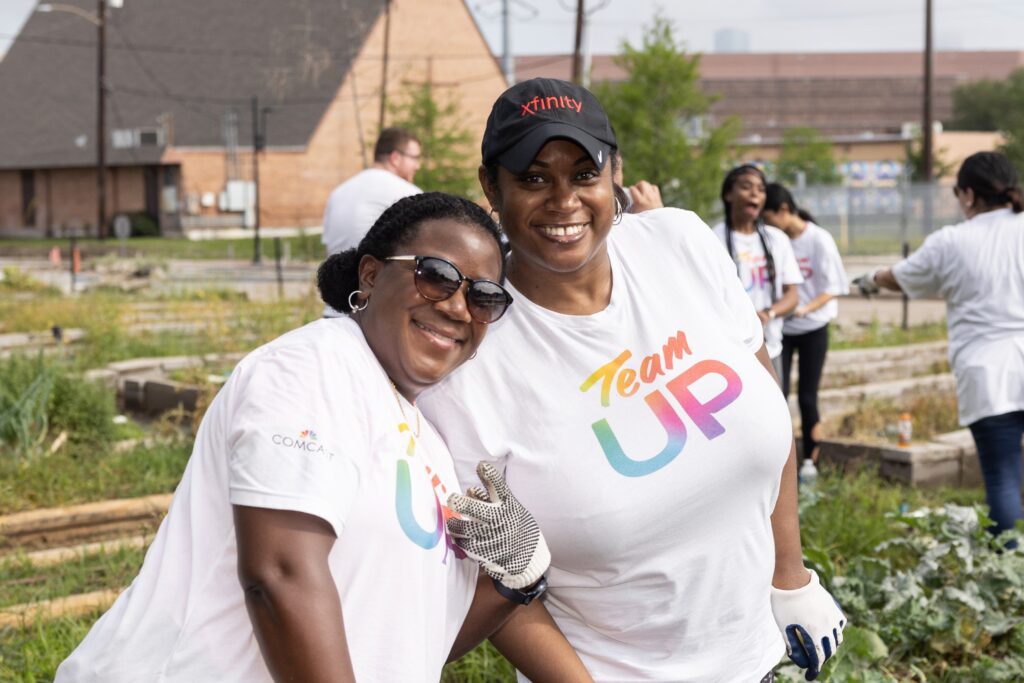 Two volunteers leaning in to each other and smiling while posing for a picture
