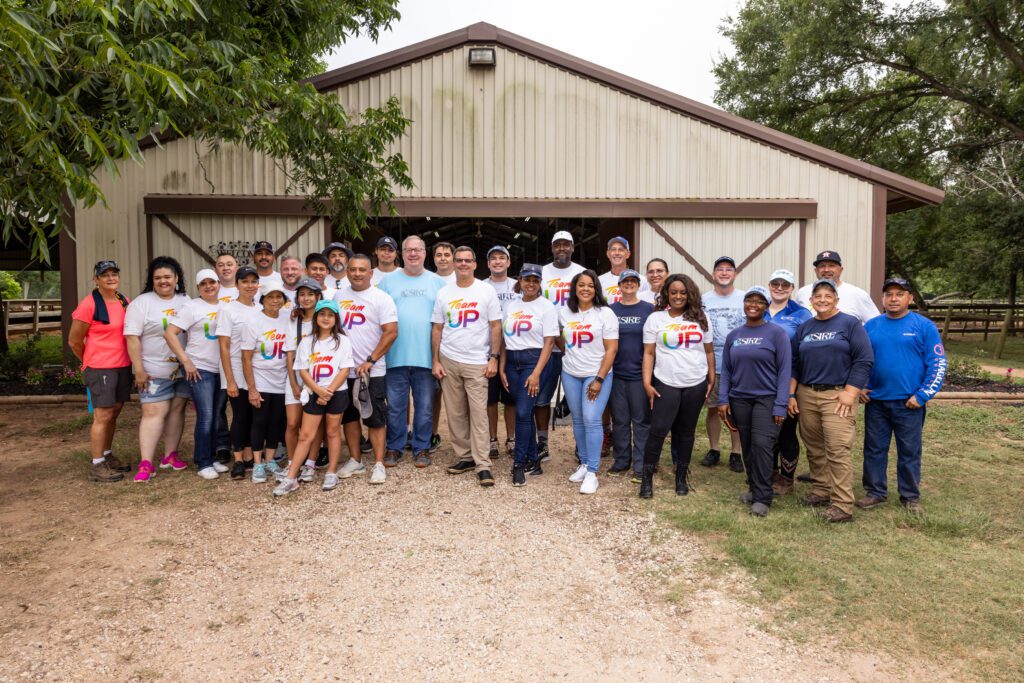 Team UP volunteers gather for a group photo at the SIRE Therapeutic Horsemanship stables in Fulshear, Texas.