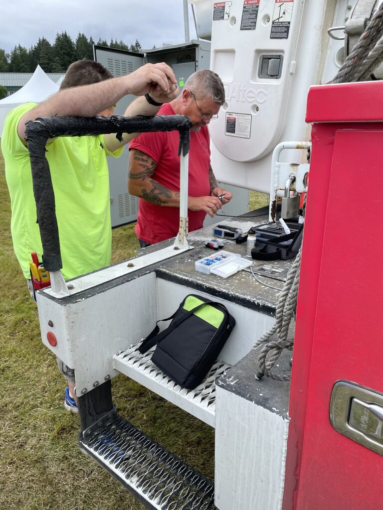 Comcast technicians work on equipment on the back of a truck. 