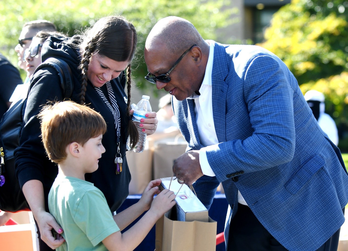 Comcast's Broderick Johnson hand a boy a bag.