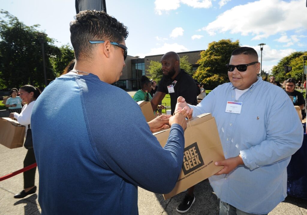 Freegeek's Juan Muro hands out a bag outside.