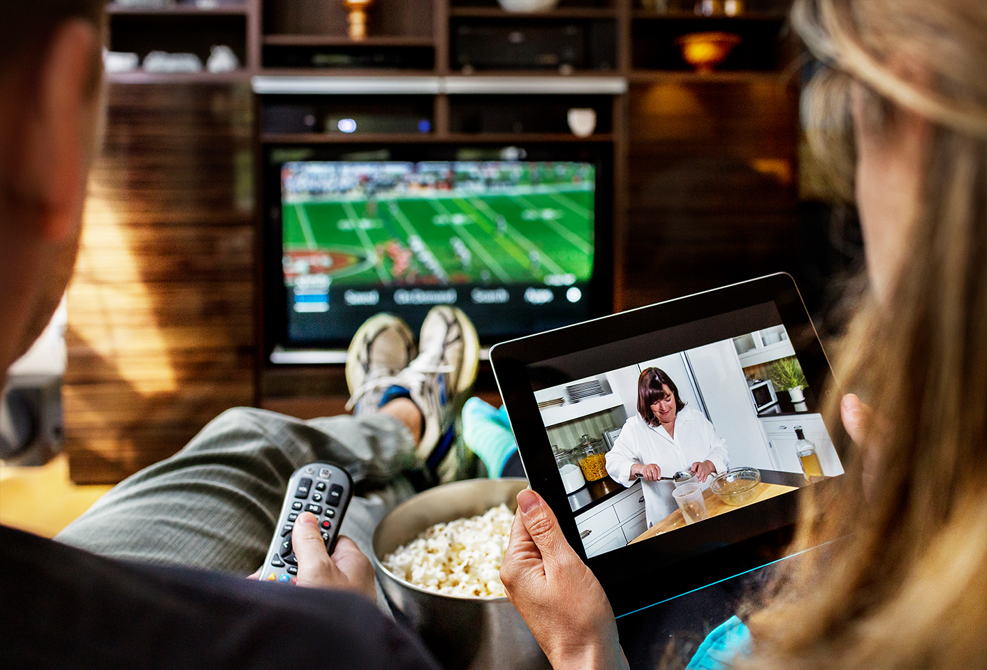 Two people watching TV using a television and a tablet.