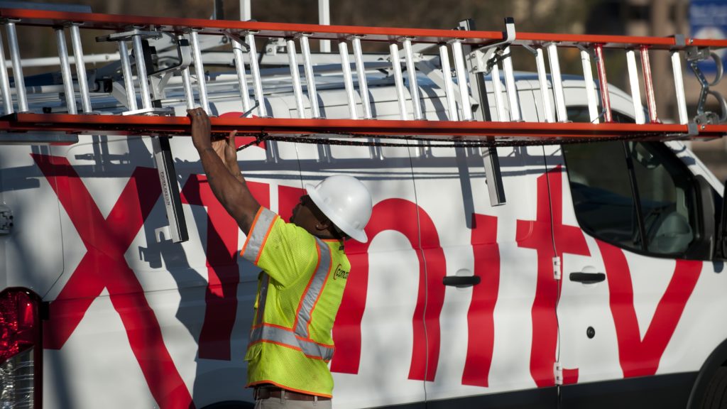 An Xfinity technician removes a ladder from an Xfinty van.