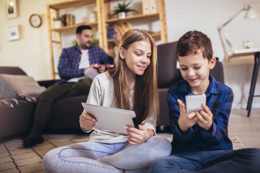 A family on various electronic devices in their home, including two children on a tablet and cell phone. With recent expansion to Southeast Georgia, consumers are experiencing the fast and reliable Xfinity Internet for the first time.