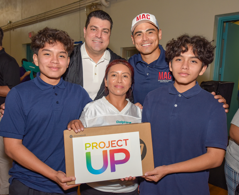 Three adults and two kids posing with a laptop