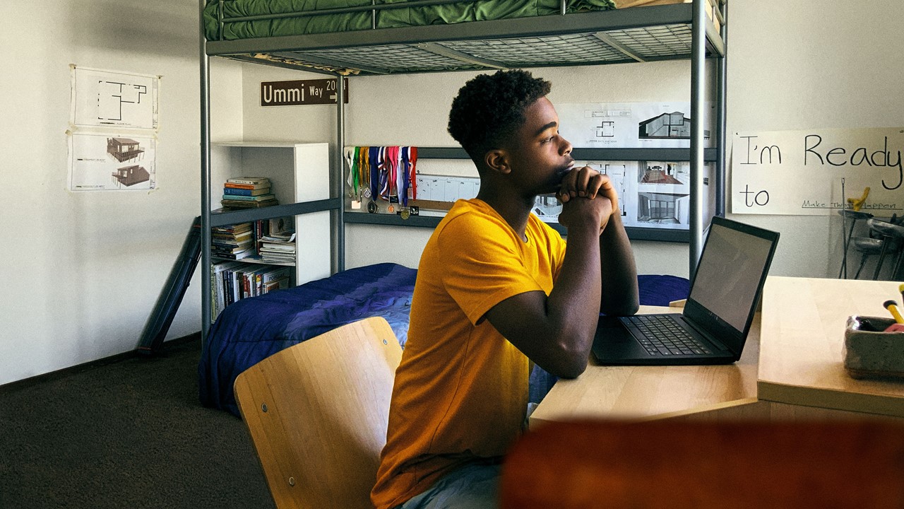 student working at laptop in his bedroom