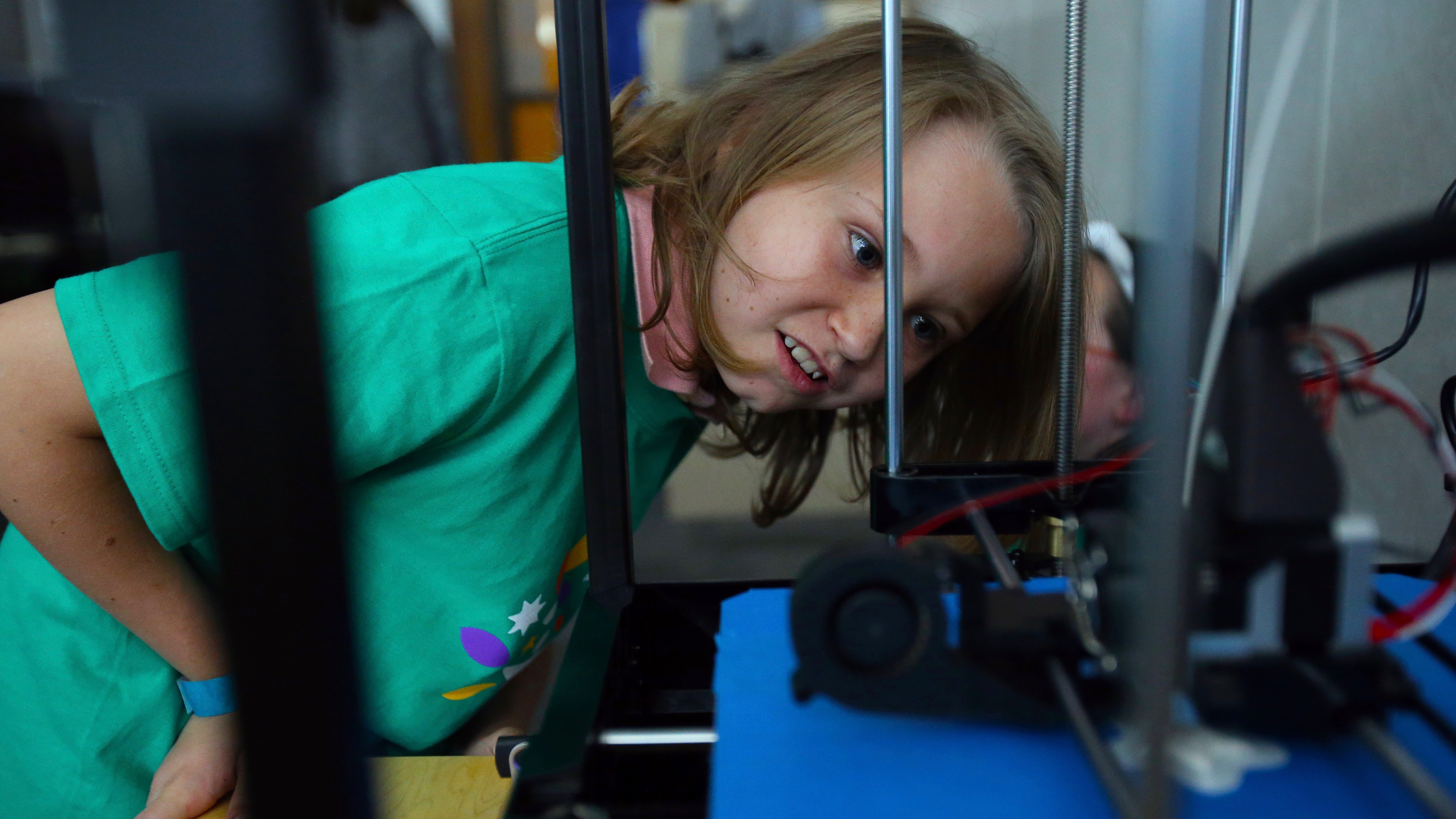 A young Comcast Cares Day volunteers examines some machinery.