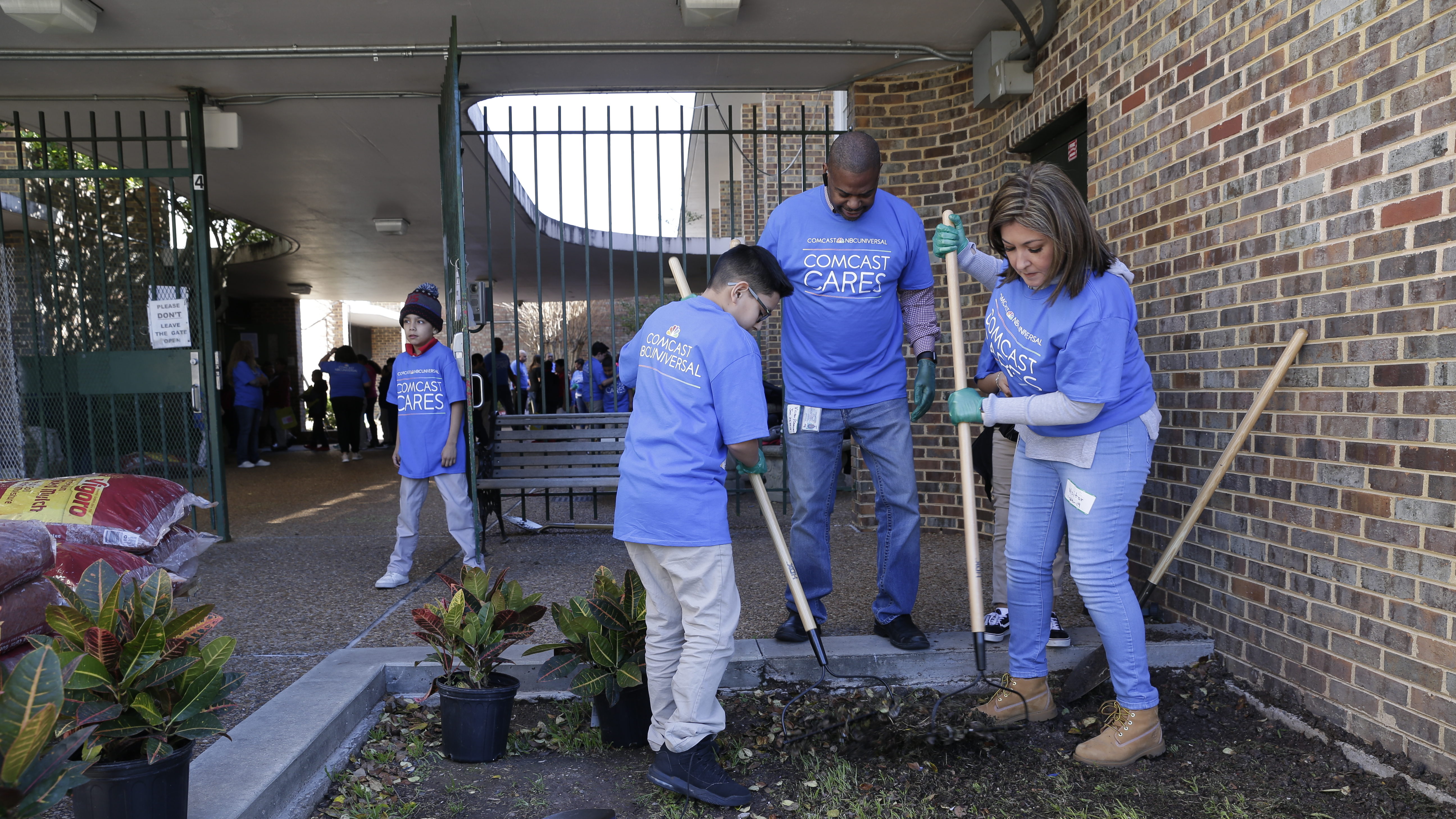 Comcast Cares Day volunteers rake a garden bed.