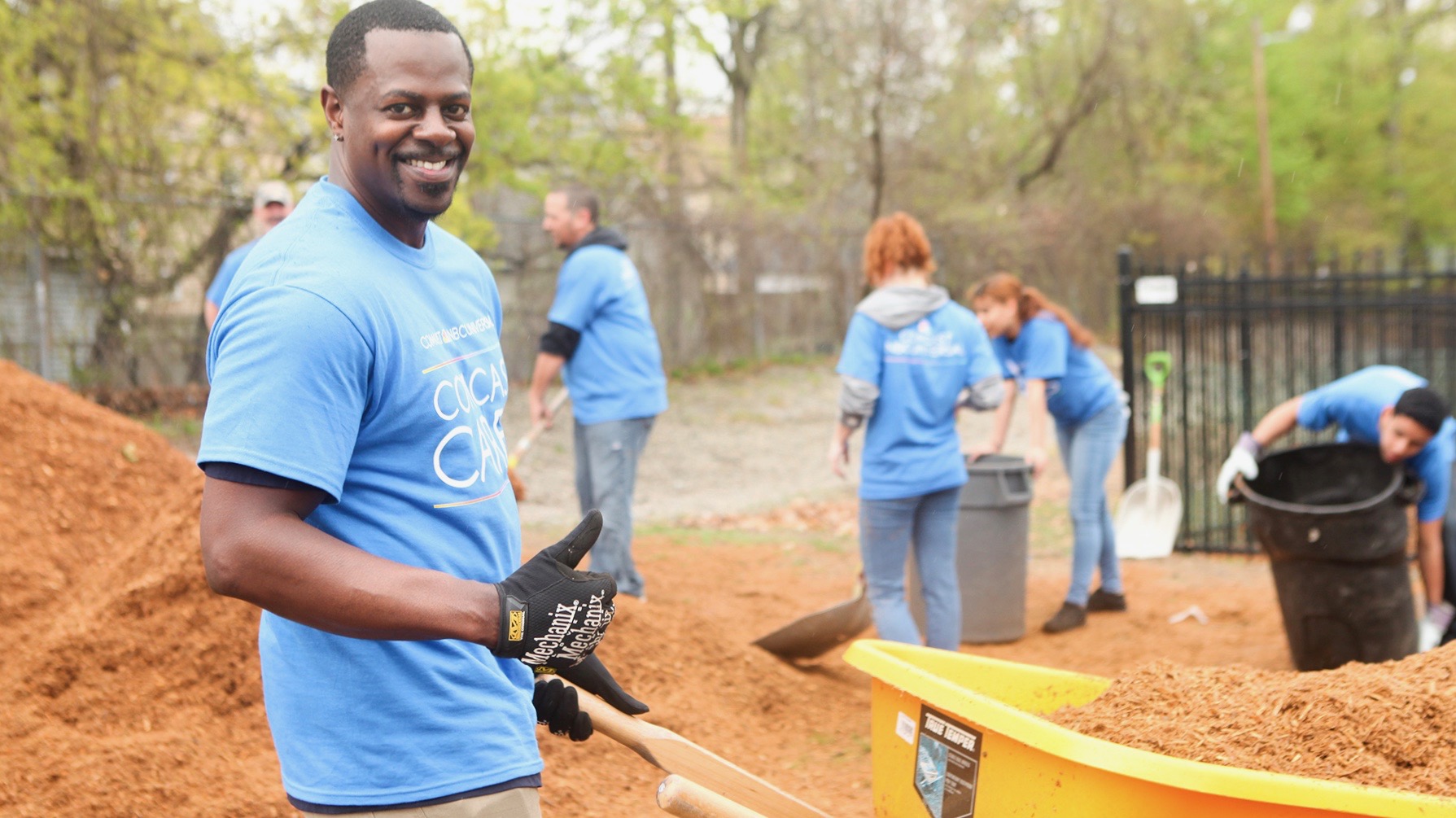 Comcast Cares Day volunteers carry mulch in wheelbarrows.