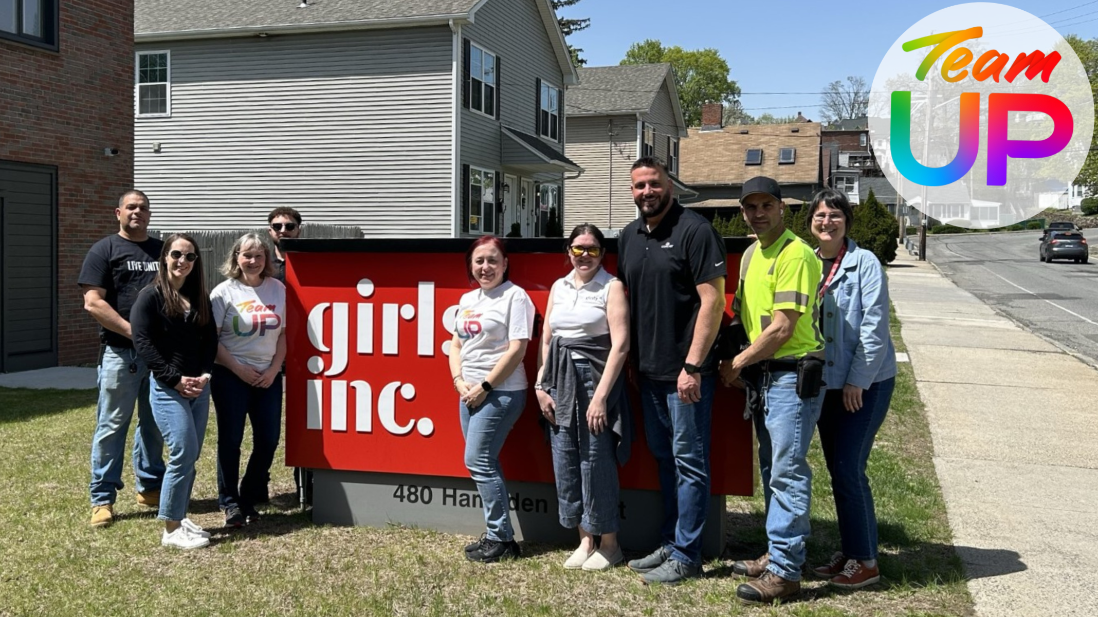 Team Up volunteers in front of girls inc. sign